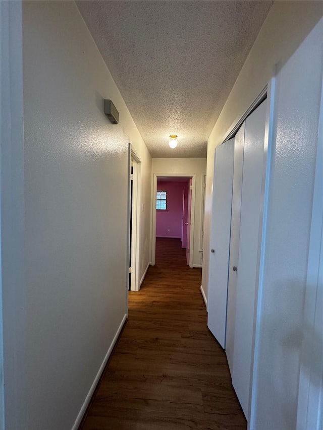 hallway featuring dark hardwood / wood-style floors and a textured ceiling