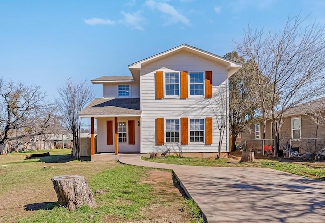 traditional-style home featuring a shingled roof, a porch, and a front yard