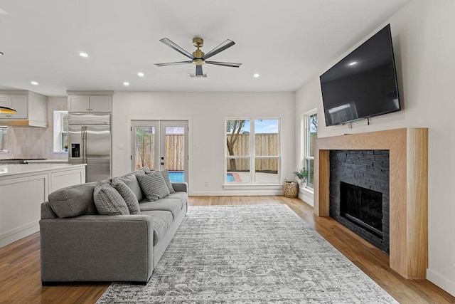 living area featuring french doors, a fireplace, light wood-style flooring, and recessed lighting