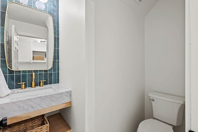 bathroom with toilet, tasteful backsplash, and a sink