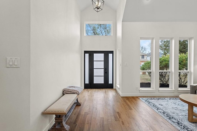 entrance foyer with a notable chandelier, a towering ceiling, baseboards, and wood finished floors