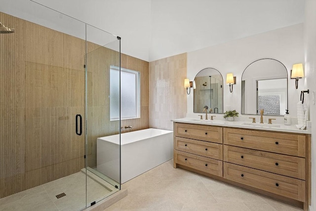 full bath featuring a freestanding bath, double vanity, a stall shower, and a sink