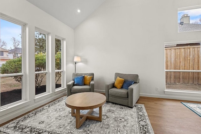 sitting room with lofted ceiling, recessed lighting, wood finished floors, and baseboards