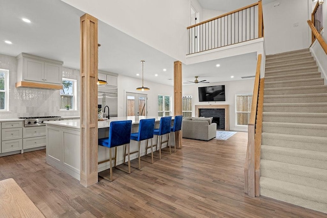 kitchen featuring light wood-style flooring, a kitchen island with sink, open floor plan, light countertops, and appliances with stainless steel finishes