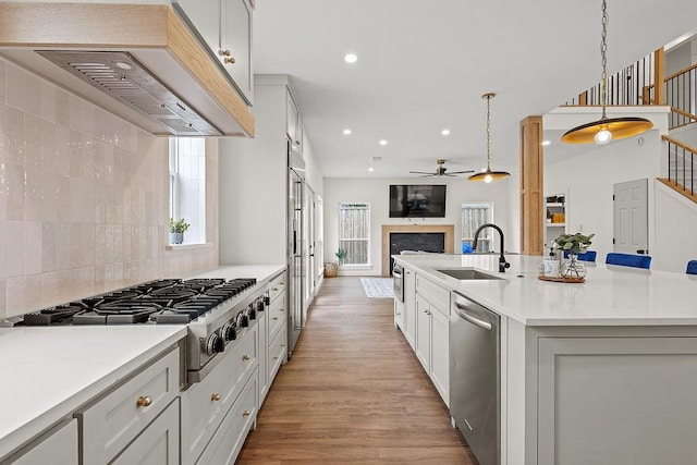 kitchen featuring a center island with sink, appliances with stainless steel finishes, open floor plan, decorative light fixtures, and a sink