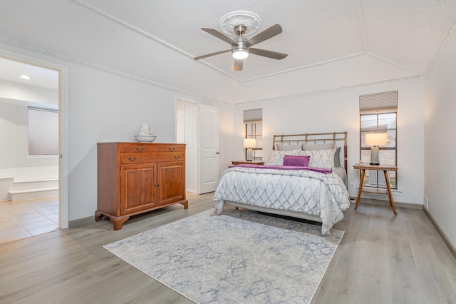 bedroom featuring light wood-type flooring, vaulted ceiling, baseboards, and ceiling fan