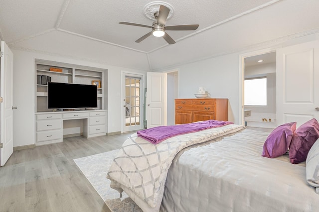 bedroom with a ceiling fan, lofted ceiling, built in desk, and light wood-style flooring