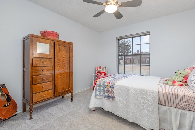 bedroom featuring light carpet, ceiling fan, and a textured ceiling