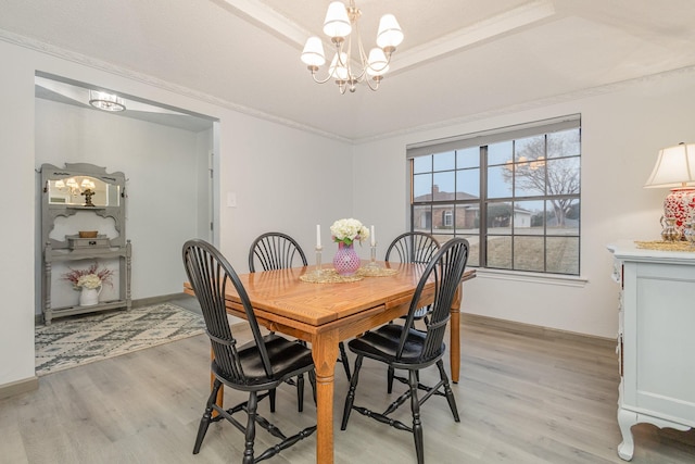 dining space with a tray ceiling, an inviting chandelier, ornamental molding, light wood-type flooring, and baseboards