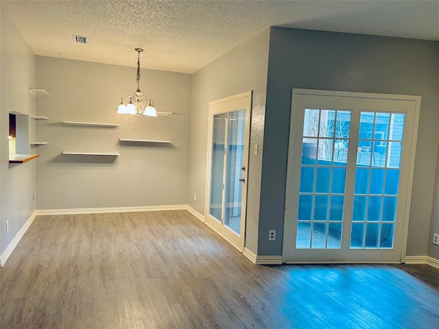 interior space with baseboards, visible vents, wood finished floors, an inviting chandelier, and a textured ceiling