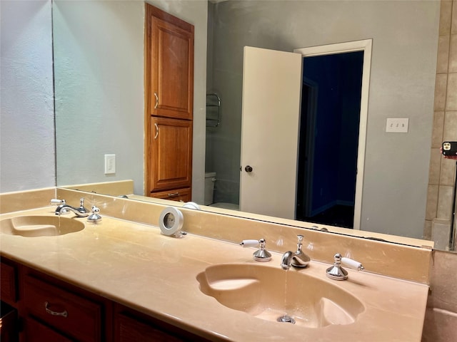 full bath with double vanity, a sink, and toilet