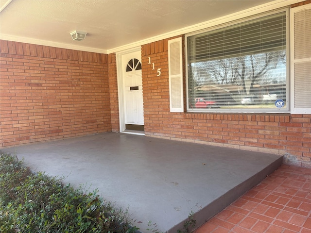 entrance to property with brick siding and a porch