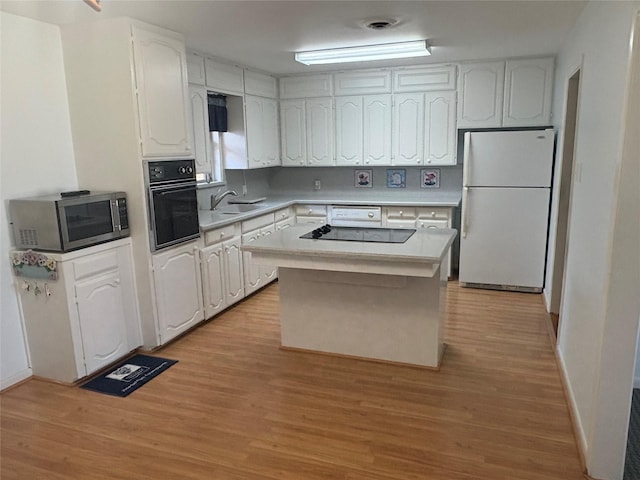 kitchen featuring light wood-type flooring, black appliances, white cabinets, and a center island