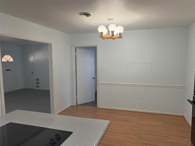 interior space featuring black electric cooktop, an inviting chandelier, and wood-type flooring