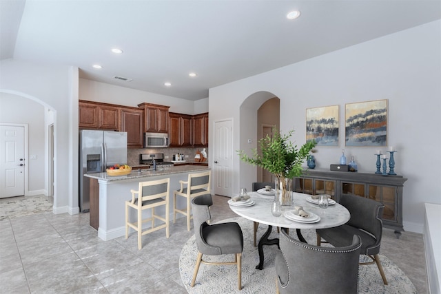 dining area with arched walkways, light tile patterned floors, recessed lighting, visible vents, and baseboards