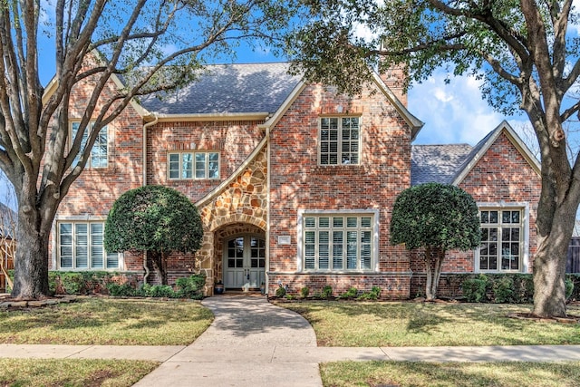 english style home featuring a front lawn and french doors