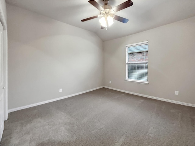 spare room featuring lofted ceiling, dark colored carpet, and ceiling fan