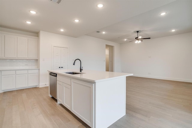 kitchen featuring an island with sink, white cabinetry, light wood-type flooring, sink, and dishwasher