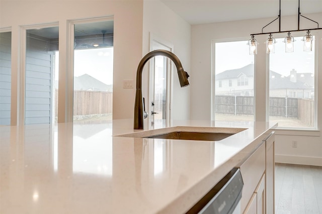 interior space featuring light hardwood / wood-style floors, pendant lighting, sink, and dishwasher