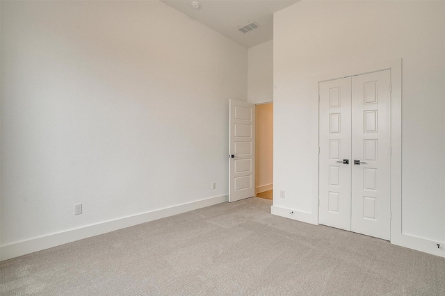 unfurnished bedroom with a high ceiling, light carpet, and a closet