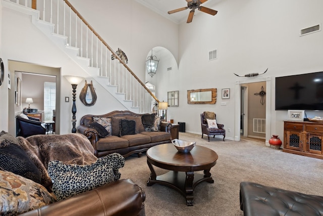 living room with ceiling fan, carpet, and a towering ceiling