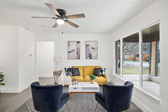 living room with wood finished floors, a ceiling fan, and baseboards