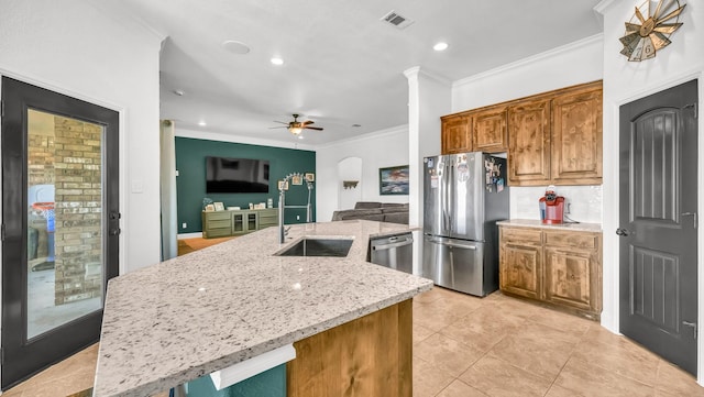 kitchen with a center island with sink, brown cabinetry, open floor plan, stainless steel appliances, and a sink