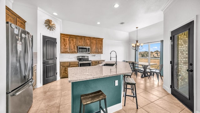 kitchen with a breakfast bar, stainless steel appliances, hanging light fixtures, a kitchen island with sink, and a sink