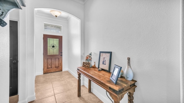 foyer with arched walkways, a textured wall, light tile patterned floors, baseboards, and crown molding