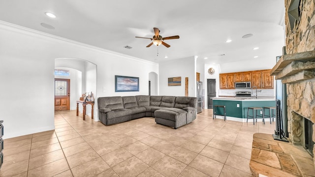 living room featuring ornamental molding, arched walkways, visible vents, and light tile patterned floors