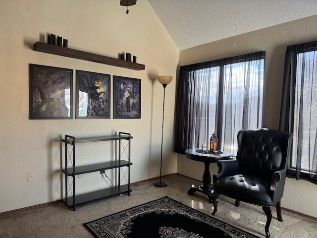 sitting room with lofted ceiling, baseboards, carpet floors, and a textured ceiling