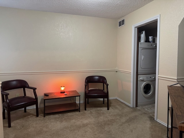 living area with visible vents, a textured wall, stacked washer / drying machine, a textured ceiling, and carpet flooring