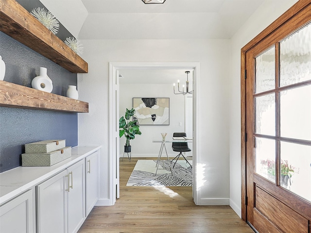 hallway with light hardwood / wood-style floors and an inviting chandelier