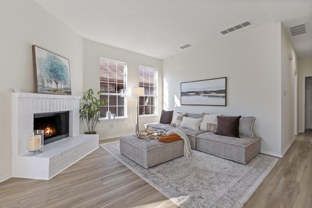 living room with wood finished floors, a fireplace, and visible vents