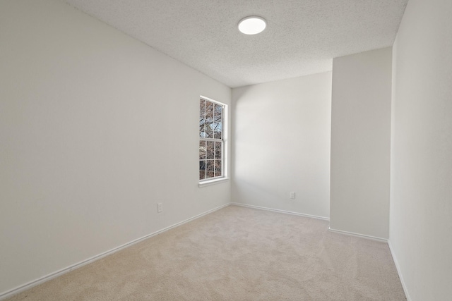 unfurnished room with carpet flooring, a textured ceiling, and baseboards