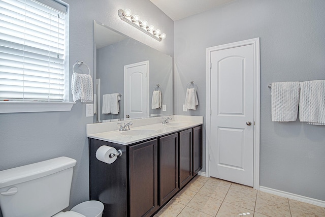 bathroom with a sink, toilet, double vanity, and tile patterned flooring