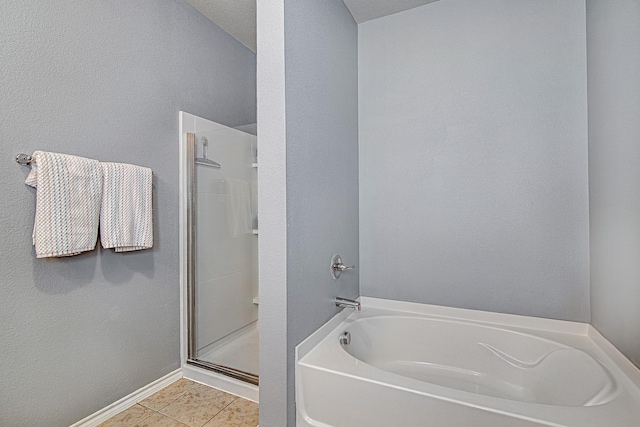 bathroom featuring tile patterned floors, a stall shower, baseboards, and a garden tub