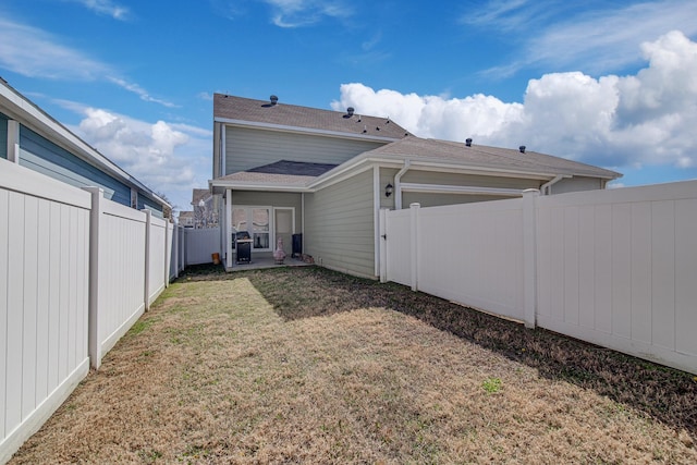 rear view of house with a garage, a lawn, and a fenced backyard