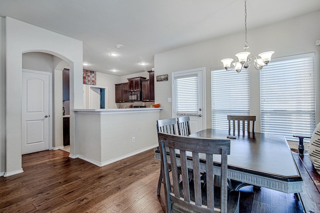 dining space with dark wood finished floors, a notable chandelier, arched walkways, and baseboards