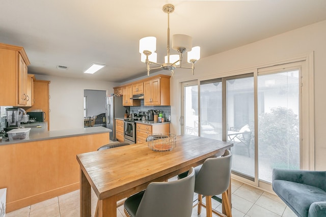 interior space featuring appliances with stainless steel finishes, tasteful backsplash, pendant lighting, light tile patterned floors, and sink