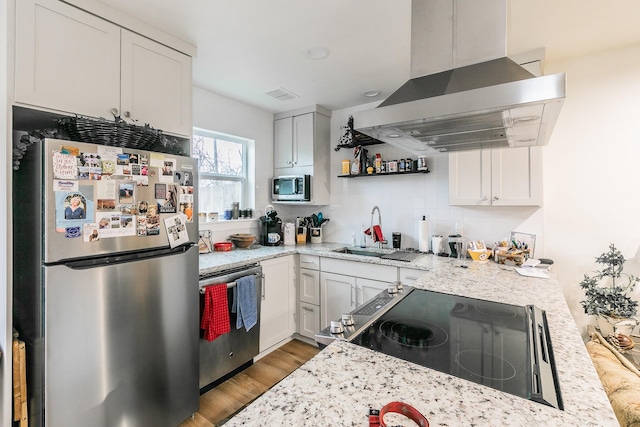 kitchen featuring white cabinets, light wood-type flooring, island range hood, and stainless steel appliances