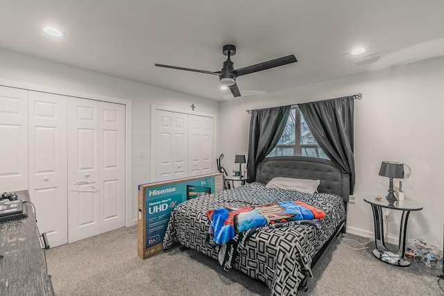 carpeted bedroom with ceiling fan and two closets