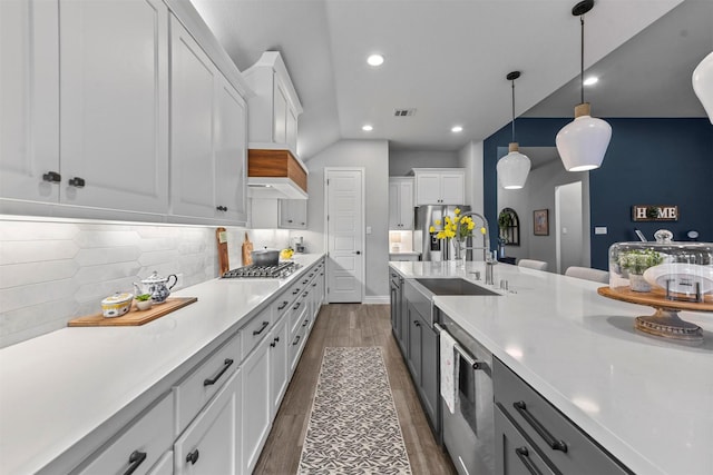 kitchen featuring stainless steel appliances, light countertops, white cabinets, and hanging light fixtures