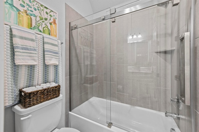 bathroom with toilet and shower / bath combination with glass door