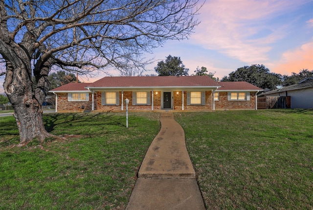 ranch-style home with brick siding and a yard