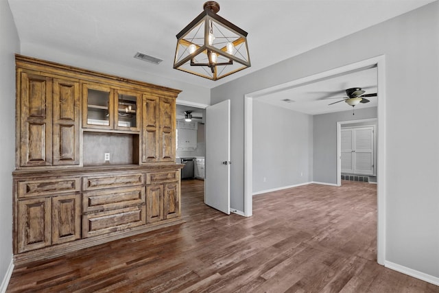 unfurnished dining area featuring dark wood-style floors, visible vents, baseboards, and ceiling fan with notable chandelier