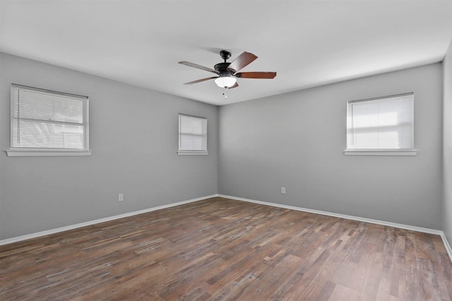 spare room with baseboards, dark wood-style flooring, and a ceiling fan