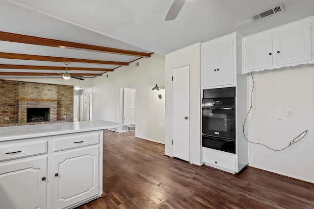 kitchen featuring visible vents, open floor plan, oven, light countertops, and white cabinetry