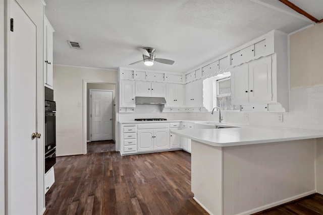 kitchen featuring light countertops, white cabinetry, a sink, a peninsula, and under cabinet range hood