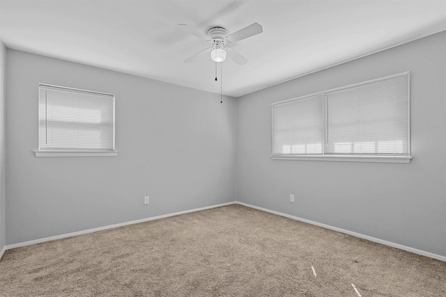 carpeted spare room with ceiling fan and baseboards